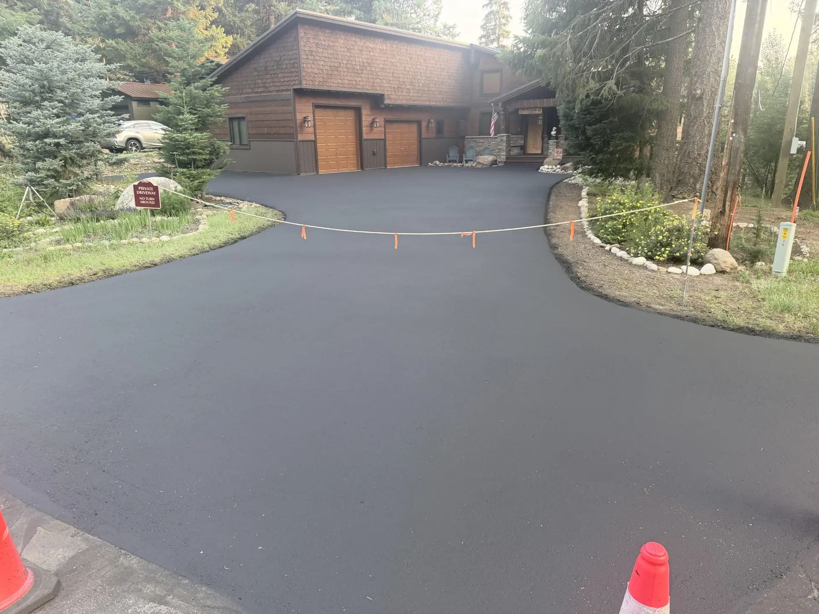 Large curved driveway at a wood-sided home after sealcoating by Supreme Seal Coat
