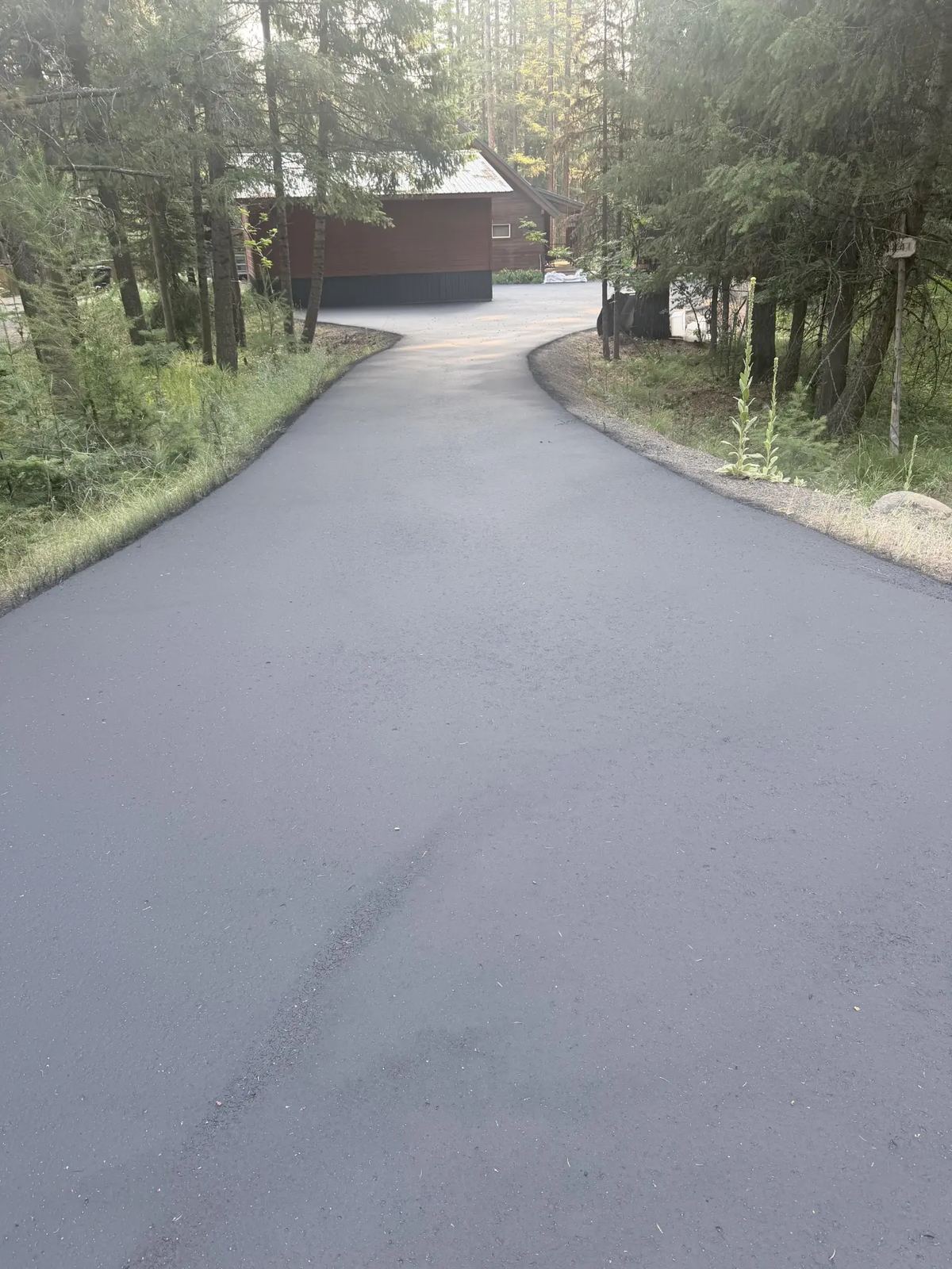 Long wooded residential driveway freshly sealcoated by Supreme Seal Coat